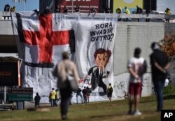 Manifestantes despliegan una enorme manta con una caricatura en que se muestra al presidente Jair Bolsonaro, brocha en mano, cambiando el emblema de la Cruz Roja en una esvástika, el símbolo nazi, durante protestas en junio.