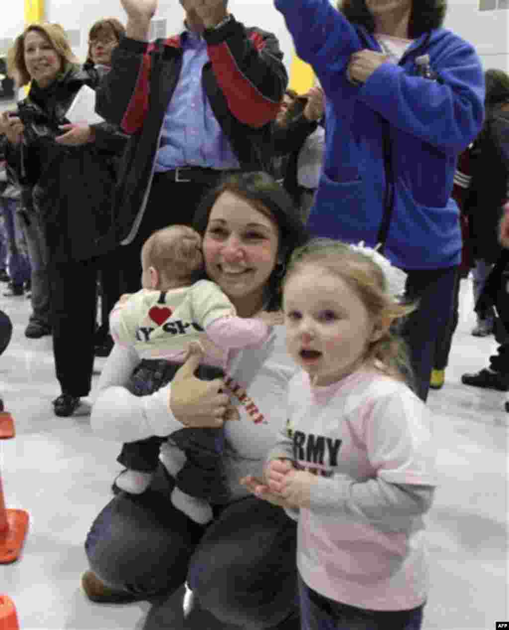 Amanda Richard of Milton, Vt., holds daughter Mckenzie as her other daughter, Michaela, right front, as they watch for her husband, Spc. Ryan Richard, during a homecoming for Vermont National Guard troops on, Monday, Nov. 22, 2010 in South Burlington, Vt.