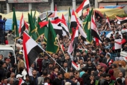 Protesters holding Popular Mobilization forces and Iraqi flags and chanting religious slogans march toward Tahrir Square in Baghdad, Iraq, Dec. 6, 2019.