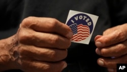 Carlos Salas, de 78 años, quien recientemente se convirtió en ciudadano estadounidense y votó en su primera elección, sostiene una calcomanía con la leyenda "Yo voté" en su estudio, el domingo 3 de noviembre de 2024, en Alamo, Texas. [Foto: Archivo/AP]