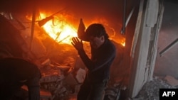 FILE - A Syrian man searches for people in a fire following airstrikes on the rebel-held besieged town of Douma in the eastern Ghouta region, on the outskirts of the capital, Damascus, Feb. 7, 2018.