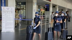 Para pramugari sebuah maskapai penerbangan India, tiba di bandara saat Pemerintah mulai membuka kembali layanan penerbangan domestik setelah dua bulan ditutup akibat pandemi corona di Ahmedabad, India, Senin, 25 Mei 2020. (Foto AP / Ajit Solanki)