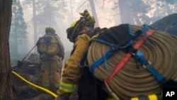 FIRE - Two firefighters from Cosumnes Fire Department carry hoses while holding a fire line to keep the Caldor Fire from spreading in South Lake Tahoe, Calif., Sept. 3, 2021. 