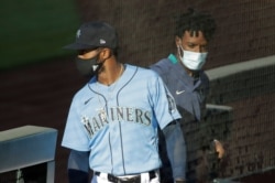 Seattle Mariners' Mallex Smith, left, and Dee Gordon, right, wear masks as they enter the dugout, Monday, July 20, 2020, during a "summer camp" baseball scrimmage game in Seattle. (AP Photo/Ted S. Warren)