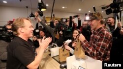 Canopy Growth CEO Bruce Linton applauds after handing Ian Power and Nikki Rose, who were first in line to purchase the first legal recreational marijuana after midnight, their purchases at a Tweed retail store in St John's, Newfoundland and Labrador, Canada, Oct. 17, 2018.