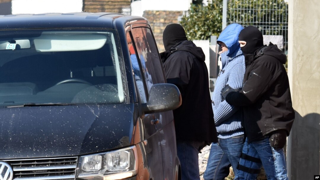 A detained man is escorted by police after a raid in the town of Michalovce, eastern Slovakia, March, 1. 2018. Police were conducting raids in eastern Slovakia on Thursday in houses linked to members of the Italian Mafia, about whom an investigative journalist was writing before he was shot dead last week.