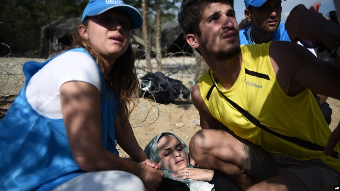 An exhausted woman collapses as she waits to cross the border from the northern Greek village of Idomeni, to southern Macedonia, Sept. 20, 2015.