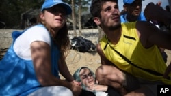 An exhausted woman collapses as she waits to cross the border from the northern Greek village of Idomeni, to southern Macedonia, Sept. 20, 2015.