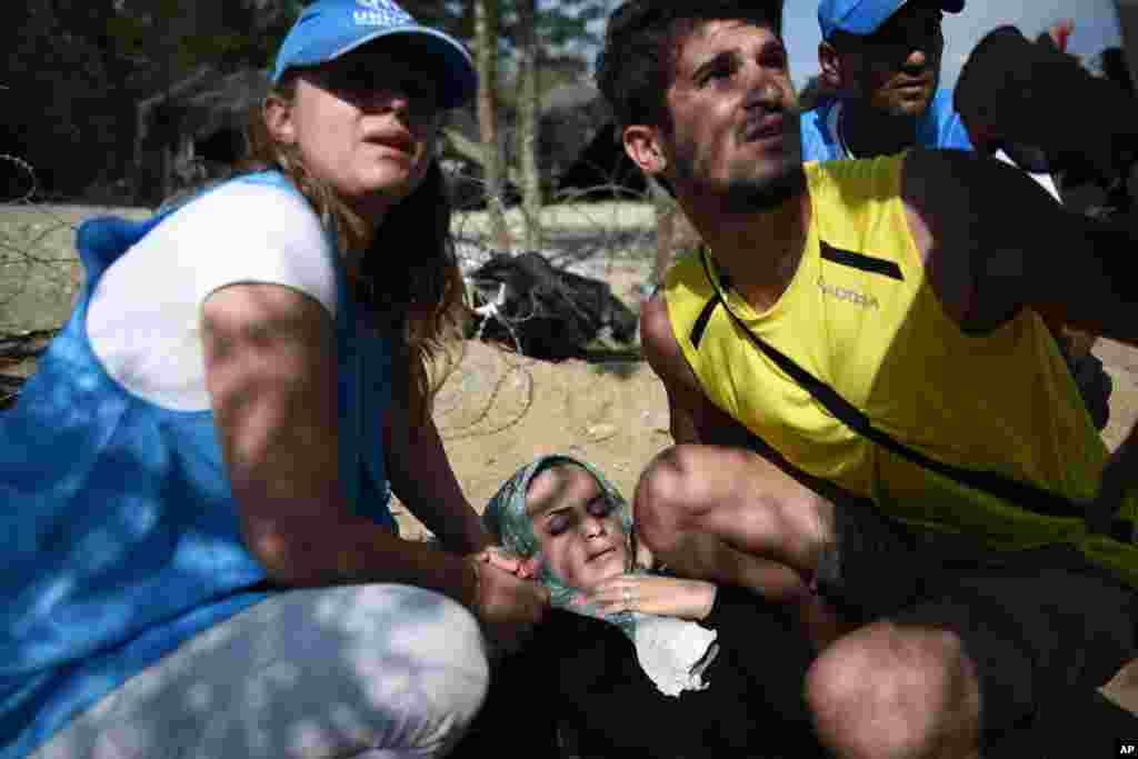 An exhausted woman collapses as she waits to cross the border from the northern Greek village of Idomeni, to southern Macedonia.