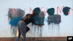 FILE - A caretaker of a building attempts to rub off anti-government graffiti in Harare, Zimbabwe, Sept. 6, 2016. Protests have rocked Zimbabwe since July, calling on President Robert Mugabe to fix the economy and respect human rights.