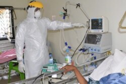 FILE - A medical staff member wearing personal protective equipment (PPE) tends to a COVID-19 coronavirus patient in the infectious diseases department at the Donka hospital in Conakry on May, 13 2020.