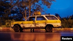 FILE - A driver looks for tools to replace a flat tire on a public transport car in Bamako, Mali.