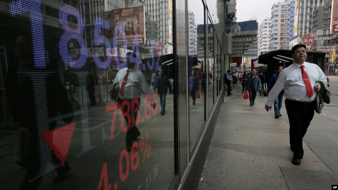 Seorang pria berjalan di dekat layar yang menunjukkan indeks saham di Hong Kong Stock Exchange. Saham-saham Hong Kong mengalami penurunan terbesar selama 6 bulan terakhir Kamis (11/2).