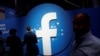 FILE - Attendees walk past a Facebook logo during Facebook Inc's F8 developers conference in San Jose, California, United States.