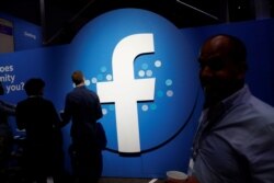 FILE - Attendees walk past a Facebook logo during Facebook Inc.'s F8 developers conference in San Jose, Calif.