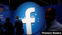 FILE - Attendees walk past a Facebook logo during Facebook Inc's F8 developers conference in San Jose, California, United States.