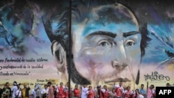 Partidarios del presidente Nicolás Maduro junto a una pared con un retrato del Libertador Simón Bolivar durante una marcha, en Caracas el 12 de septiembre de 2024.