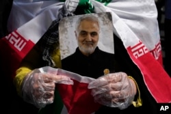 Seorang jamaah memegang potret mendiang Jenderal Garda Revolusi Iran Qassem Soleimani, yang tewas dalam serangan drone AS pada 2020 di Irak. (Foto: AP)