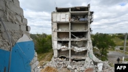Osoba prolazi pored stambene zgrade uništene kao rezultat neprijateljstava 2022. godine u gradu Izjum, oblast Harkov, 10. septembra 2023. godine, tokom prve godišnjice oslobođenja malog grada na istoku Ukrajine.