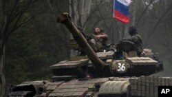 Pemberontak pro-Rusia mengendarai tank berbendera Rusia di sebuah jalan di Donetsk, Ukraina timur (21/7). (AP/Vadim Ghirda)