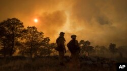 Firefighter Jake Hainey, left, and engineer Anna Mathiasen watch as a wildfire burns near Oroville, Calif., July 8, 2017. The fast-moving wildfire in the Sierra Nevada foothills destroyed structures, including homes, and led to several minor injuries, fire officials said Saturday as blazes threatened homes around California during a heat wave.