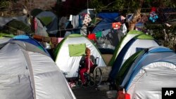 Une réfugiée assise sur une chaise roulante au milieu des tentes au port de Pirée, près d'Athènes, Grèce, 9 avril 2016.