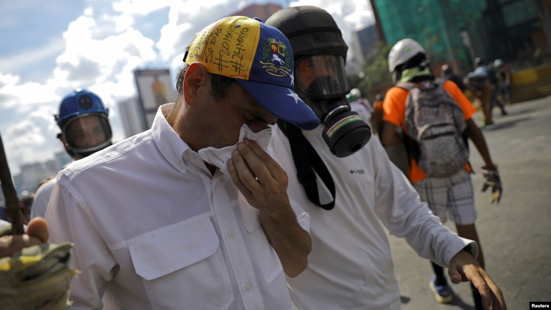 El líder opositor Henrique Capriles, centro, es auxiliado luego de ser afectado por el gas lacrimógeno y los golpes durante una protesta contra el gobierno en Caracas, el lunes 29 de mayo.