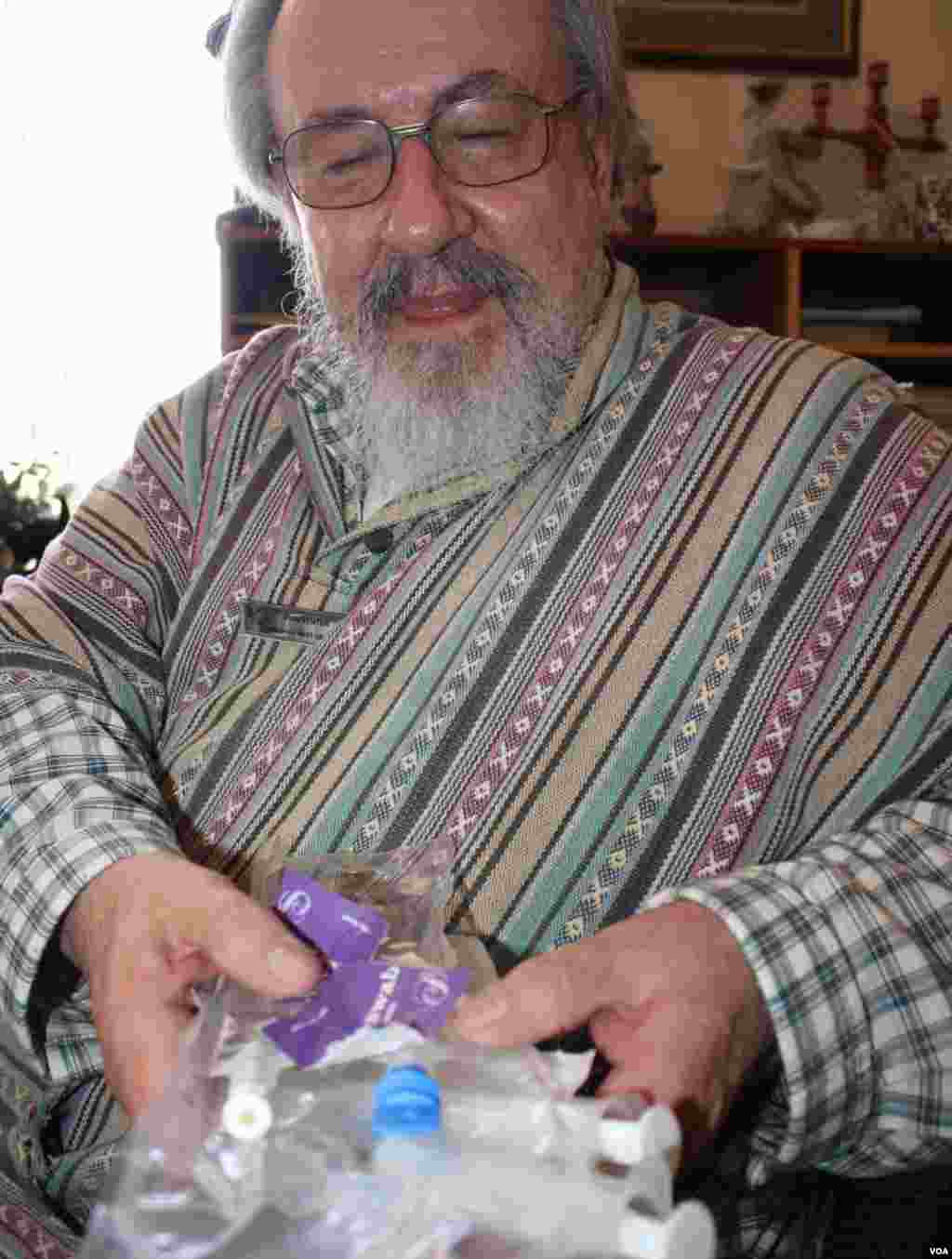 Rian Venter holds purple sachets, syringes and a plastic sheath that moments ago contained a lactate solution used by a doctor giving intravenous relief to a patient with a life-threatening liver condition at West Gauteng Hospice. (VOA / D. Taylor)