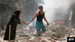 Des gens marchent dans les décombres des bâtiments détruits suite à un bombardement sur le quartier rebelle d'al-Kalasa dans la ville syrienne nord d'Alep, le 28 Avril 2016. (AFP PHOTO / AMEER ALHALBI)