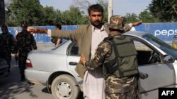 Afghan security personnel search commuters at a checkpoint in Kunduz province on April 15, 2016. 