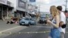 Turistas caminan cerca del lugar donde asaltantes dispararon e hirieron a dos personas que viajaban en un vehículo en la capital San José, el 10 de enero de 2024.