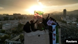 People wave flags adopted by the new Syrian rulers during celebrations in Umayyad Square, after the ousting of Syria's Bashar al-Assad, in Damascus, Syria, Dec. 20, 2024.