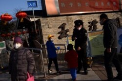 A security personnel checks temperatures of visitors entering the Yuyuantan Park, as the country is hit by an outbreak of the new coronavirus, in Beijing, China, Jan. 31, 2020.