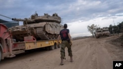 FILE - Seorang tentara Israel memindahkan tank ke truk pengangkut di daerah dekat perbatasan Israel-Lebanon, di Israel utara, 4 Desember 2024.