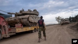 FILE - An Israeli soldier works on loading a tank onto a transport truck at an area near the Israeli-Lebanese border, as seen from northern Israel, Dec. 4, 2024. 