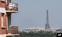 A woman enjoys the sun on her balcony as the Eiffel Tower is clearly seen in the background during the nationwide confinement to counter the conoravirus in Saint-Cloud, west of Paris, April 22, 2020.