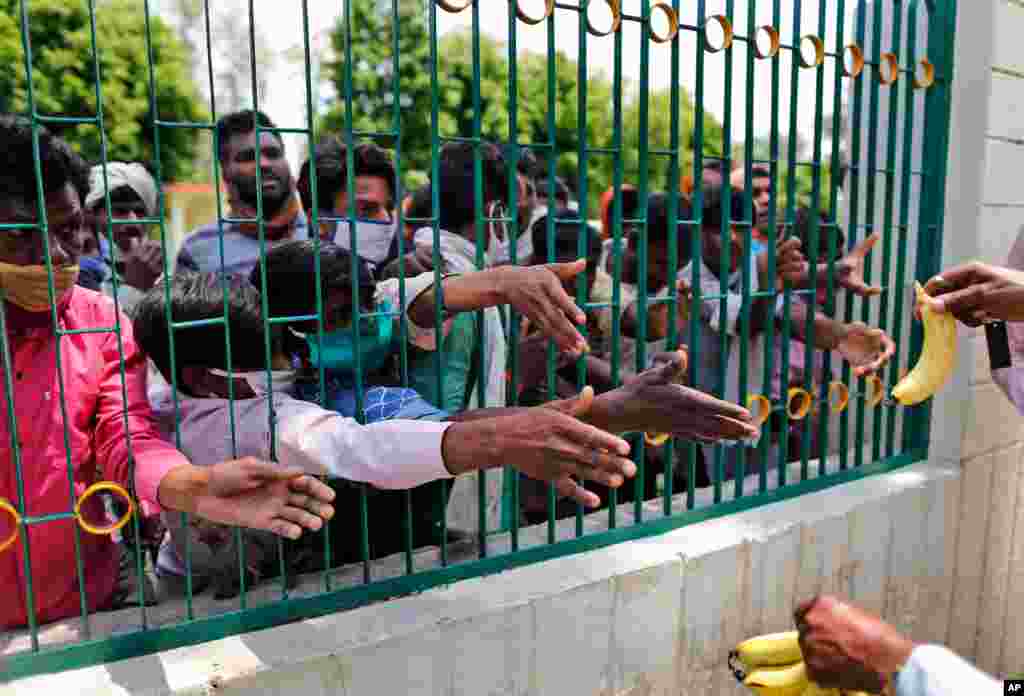 People who arrived from neighboring Madhya Pradesh state stretch their hands out to receive a banana each before boarding a bus to be transported back to their native homes in Uttar Pradesh state in Prayagraj, India.