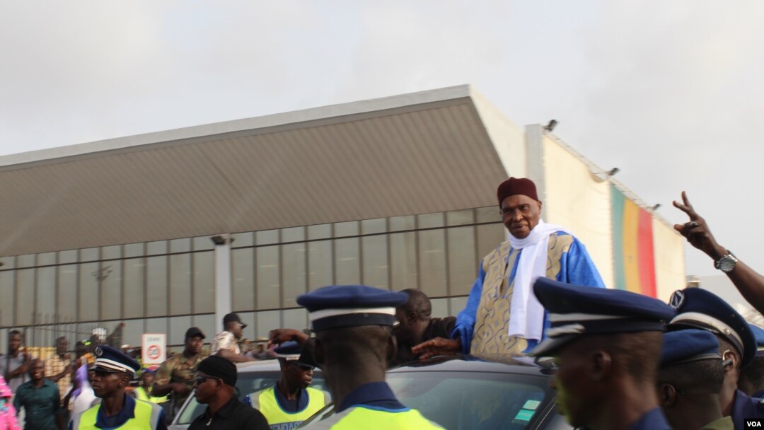 Former President Abdoulaye Wade is escorted out of Dakar international airport, Dakar, Senegal, July 10, 2017. (S. Christensen/VOA)
