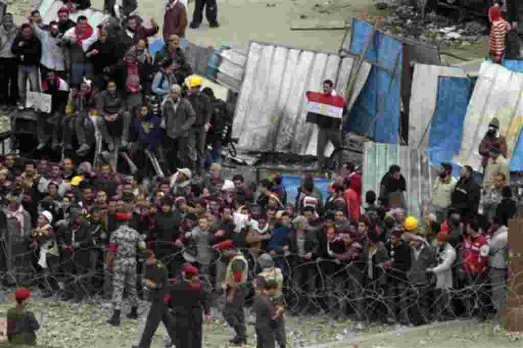Egyptian army soldiers and tanks are positioned in front of anti-government demonstrators, to prevent clashes between Mubarak supporters, unseen, and anti-government protesters who shelter behind makeshift barricades, in Tahrir square, Cairo, Egypt, Satu
