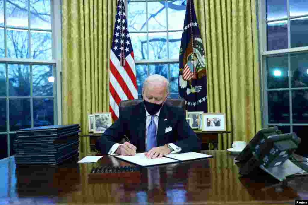 U.S. President Joe Biden signs executive orders in the Oval Office of the White House in Washington, after his inauguration as the 46th President of the United States, Jan. 20, 2021. 