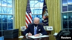 U.S. President Joe Biden signs executive orders in the Oval Office of the White House in Washington, after his inauguration as the 46th President of the United States, Jan. 20, 2021. 