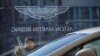 A woman cleans the window at a Aston Martin luxury car dealership in Beijing, Dec. 12, 2018. 