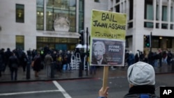 Pendukung Julian Assange memegang plakat di luar Pengadilan Westminster di London, Rabu, 6 Januari 2021.
