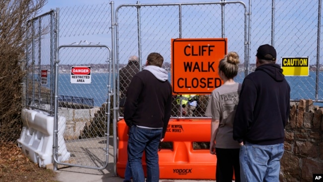 Visitors look through a barrier placed around a collapsed part of the historic Cliff Walk on March 15, 2022 in Newport, Rhode Island. (AP Photo/Charles Krupa)