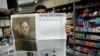 Un vendedor de la ciudad de Nueva York posa con una copia del 29 de marzo de 2024 de The Wall Street Journal que muestra una portada casi en blanco para conmemorar el primer aniversario del encarcelamiento en Rusia de su reportero Evan Gershkovich (retrato L.)