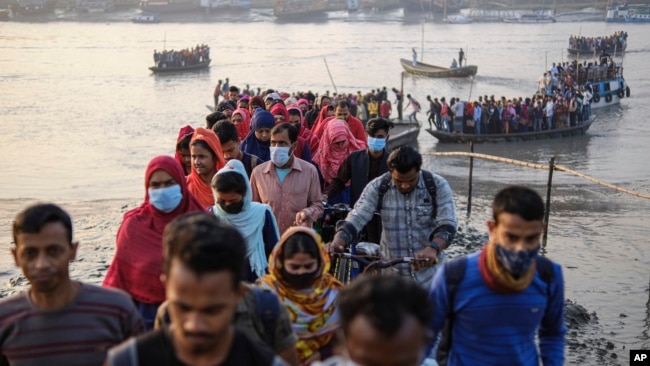 Workers walk to work at an export processing zone early in the morning after crossing the Mongla river in Mongla, Bangladesh, March 3, 2022. This Bangladeshi town stands alone to offer new life to thousands of climate migrants. (AP Photo/Mahmud Hossain Opu)