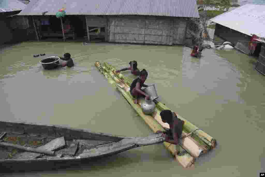 Flood-affected villagers are seen near their partly underwater houses in Gagolmari village, Morigaon district, Assam, India.