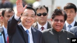 Chinese Premier Li Keqiang waves as he is received by Indian junior minister for external affairs, E. Ahamed, right, after he arrived in New Delhi, India, May 19, 2013. 