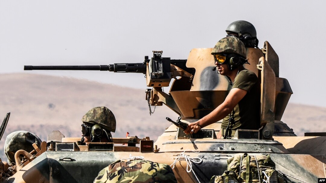 Tentara Turki duduk di atas tank menuju Suriah dari kota perbatasan Karkamis di Gaziantep (27/8). (AFP/Bulent Kilic)