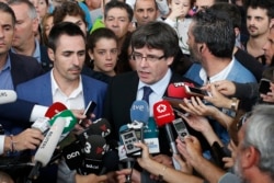 Catalan President Carles Puigdemont, center, speaks to the media at a sports center, assigned to be a polling station by the Catalan government and where Puigdemont was originally expected to vote, in Sant Julia de Ramis, near Girona, Spain, Oct. 1,
